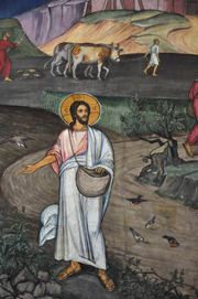 In this colorful mural, Jesus, dressed in a white tunic and surrounded by a golden halo, scatters grain along the side of the road.